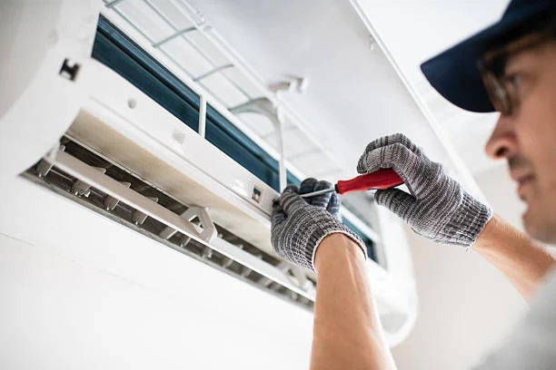 Technician cleaning and repairing an indoor wall-mounted air conditioner