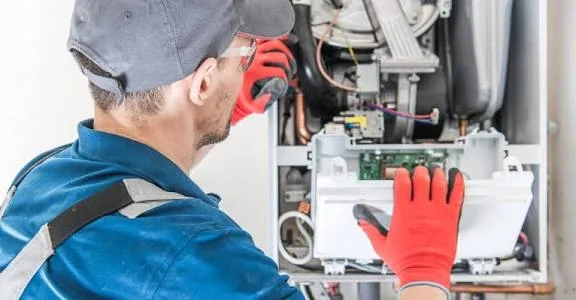 Technician inspecting components inside an open heating system cabinet