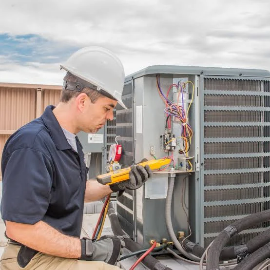 Technician troubleshooting wiring inside an outdoor air conditioning cabinet